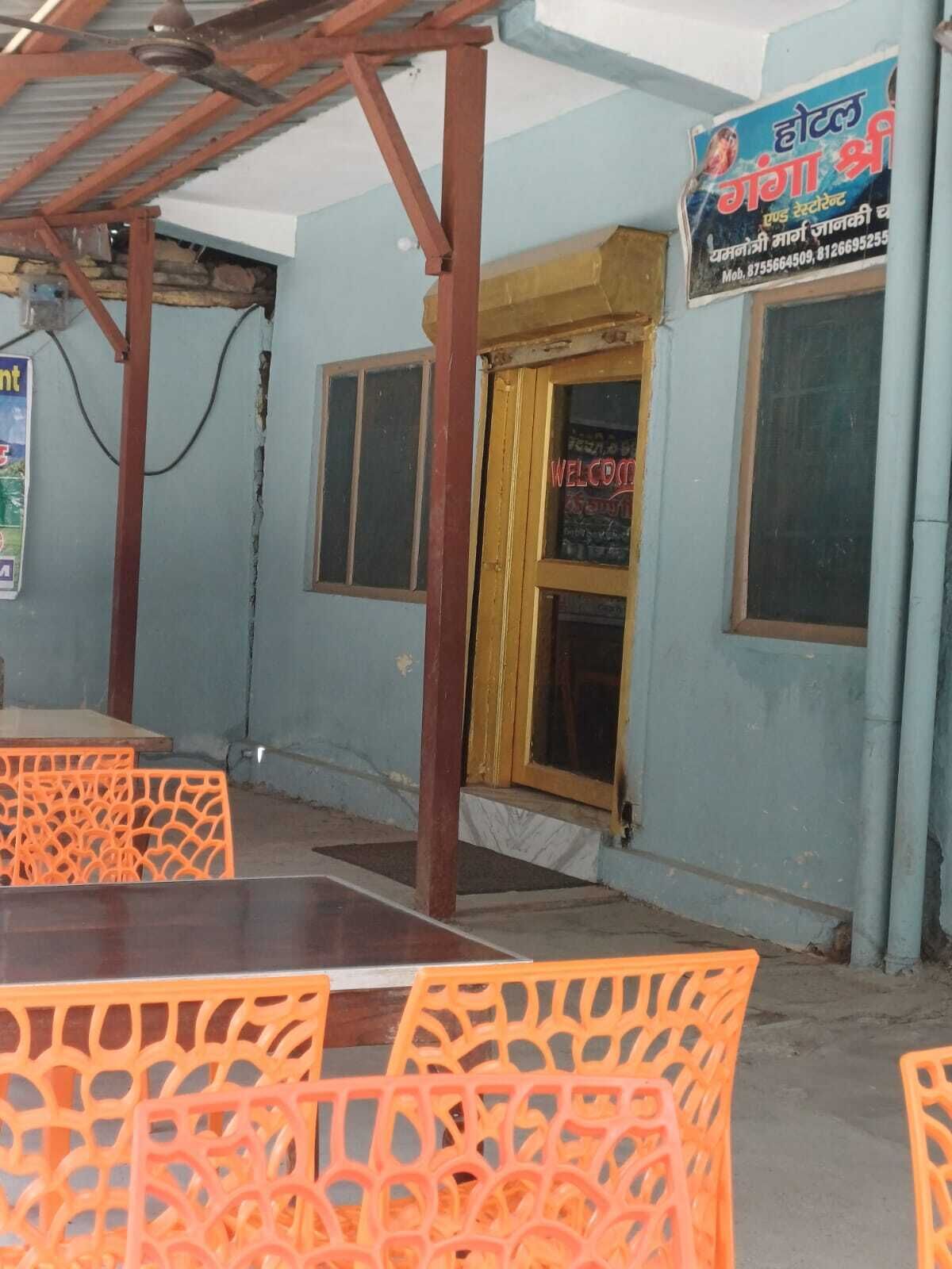 A small hotel with a 'WELCOME' sign, orange plastic chairs, and a metal roof structure.