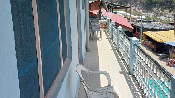 Un balcon avec des chaises en plastique, une balustrade et une vue sur un paysage montagneux.