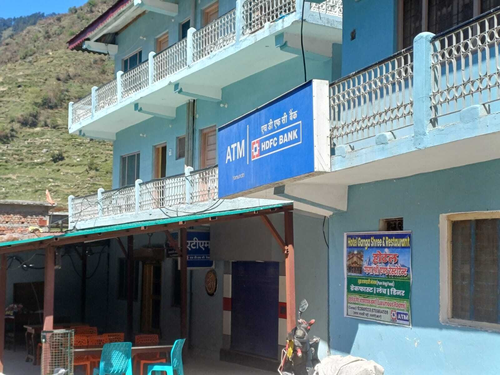 A building with an ATM sign, a restaurant advertisement, and a balcony with railings.