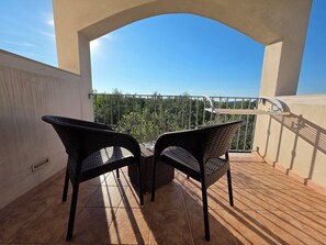 A balcony with two wicker chairs, a tiled floor, and a view of trees and sky. - Borgo Cerasa (Vieste)