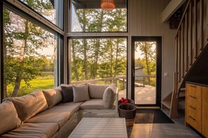 A modern interior with a large glass door leading to a deck, a sectional sofa, and a wooden cabinet. - Stay   North - Sundet (Kirkkonummi)