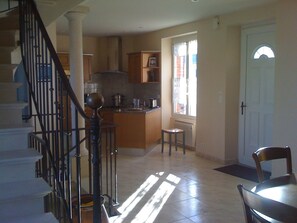 A spacious kitchen with a central island, a dining area with a table and chairs, and a staircase with a balustrade. - 5 minutes walk from the port, comfortable house, enclosed property, private parking (Cancale)