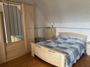 Une chambre à coucher avec un lit en bois, une commode, un miroir et une table de chevet.