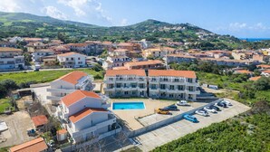 A coastal residential area with a large building featuring a swimming pool, surrounded by smaller houses and greenery. - Affittimoderni Castelsardo - LaRotonda sul Mare (Castelsardo)