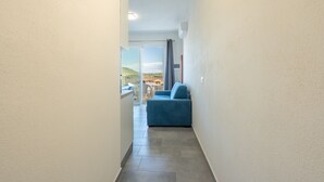 A narrow hallway with a blue sofa and a view of the outdoors. - Affittimoderni Castelsardo - LaRotonda sul Mare (Castelsardo)