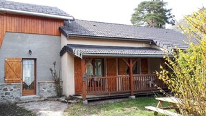 A two-story building with a stone facade, wooden shutters, and a covered porch with wooden railings.
