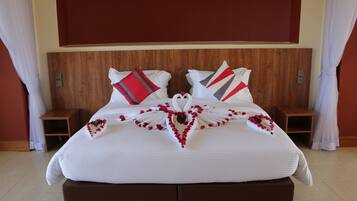 Una cama bien hecha con un arreglo floral en forma de corazón, dos mesitas de noche y un cabecero de madera.