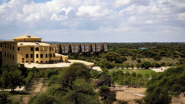 A large yellow building with multiple floors and a flat roof, surrounded by greenery and trees. - Amboseli Safari Club (Kimana)