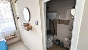 Une petite salle de bain comprenant des toilettes, un bidet et une petite poubelle.