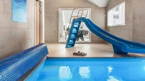 Ein Swimmingpool mit einer blauen Rutsche, einer Leiter und einem zebra-gemusterten Handtuch auf dem Boden.