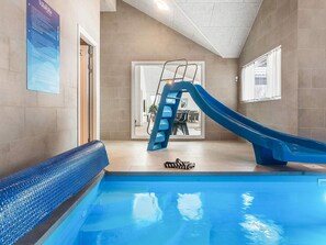 A swimming pool with a blue slide, a ladder, and a zebra-patterned towel on the floor. - 5 Star Holiday Home in Idestrup (Idestrup)
