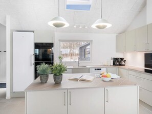 A modern kitchen with a large island, built-in appliances, and pendant lighting. - 5 Star Holiday Home in Idestrup (Idestrup)