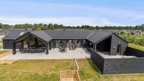 Ein modernes Gebäude mit überdachter Terrasse, großen Fenstern und einer Holzterrasse.