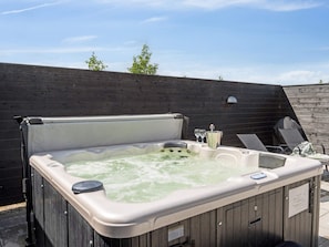 Ein Whirlpool mit Holzverkleidung, einer eingebauten Sitzgelegenheit und einem kleinen Tisch mit einem Glas und einem Behälter.