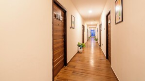 Un pasillo con pisos de madera, puertas y cuadros en las paredes.