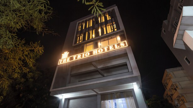 Un edificio con un cartel que dice 'The Trio Hotels' de noche.
