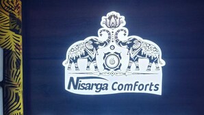 A sign for Nisarga Comforts Lodge with a prominent logo and the word "Lodge" in large letters. - Nisarga Comforts (Chikkamagaluru)