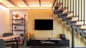 A modern living room with a flat-screen TV, a staircase, and a dining area with a table and chairs. - Modern Loft - Rho Fiera & San Siro - Milan (Milano)