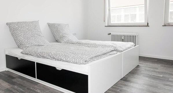 A modern, minimalist bedroom with a built-in bed, white walls, and a radiator. - 10 - Bachwiesenstr. Stuttgart (Stuttgart)