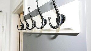 A black metal coat rack with five hooks against a white wall. - 06 - Bachwiesenstr. Stuttgart (Stuttgart)