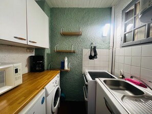 Eine kleine Küche mit Waschmaschine, Mikrowelle und Spüle.