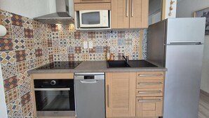 A compact kitchen with a microwave, dishwasher, oven, and refrigerator. The backsplash features a geometric tile pattern. - Cozy apartment in Cauterets with parking and wifi (Cauterets)