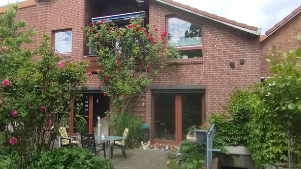 A brick house with a garden, a patio with chairs, and a window. - Beautiful 3 room trade fair apartment (Hannover)