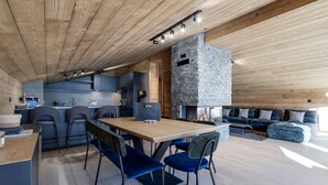 A modern kitchen with a stone fireplace, wooden ceiling, and a dining area with blue chairs. - Luxury duplex near Val d'Isère center, 4 bedrooms, parking (Val-d'Isère)
