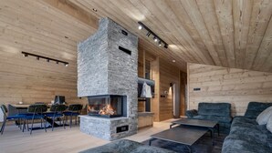 A modern interior with a stone fireplace, wooden walls, a sofa, and a dining area. - Luxury duplex near Val d'Isère center, 4 bedrooms, parking (Val-d'Isère)
