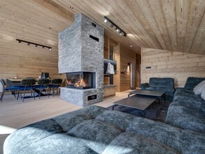 Ein modernes Interieur mit Kamin aus Stein, Holzwänden, einer Couch und einem Essbereich.