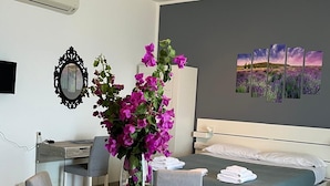 Una habitación de hotel moderna con zona de comedor, cama con vistas y un amplio ventanal.