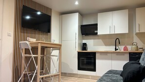A modern kitchen with white cabinets, a black oven, a microwave, and a kettle on the counter.