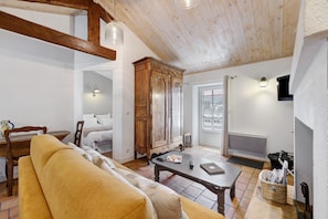 Un salon chaleureux avec un plafond en bois, un canapé, une table et un meuble.