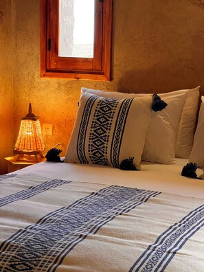 Una cama con almohadones estampados y una lámpara de noche.