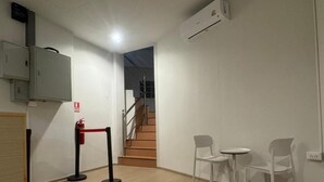 Ein Hotelzimmer mit Holzboden, weißen Wänden, einer Treppe und zwei weißen Stühlen.