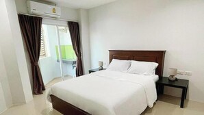Ein Hotelzimmer mit einem großen Bett, einem Nachttisch, einer Lampe und einer Klimaanlage.