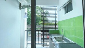 Eine kleine Küche mit Spüle, grünen Fliesen und einem Fenster mit Rollläden.