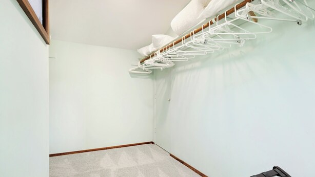 A small, carpeted room with a wooden floor, a white wall, and a black chair. - Ocean View w/AC - Wailea Elua 306 (Kihei)