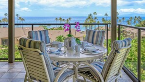 A round table with chairs and a view of the ocean. - Ocean View w/AC - Wailea Elua 306 (Kihei)