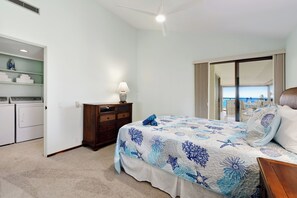 Ein Schlafzimmer mit Bett, Kommode, Waschmaschine und Blick nach draußen.