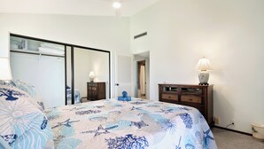 A bedroom with a bed, a dresser, a mirror, and a walk-in closet. - Ocean View w/AC - Wailea Elua 306 (Kihei)
