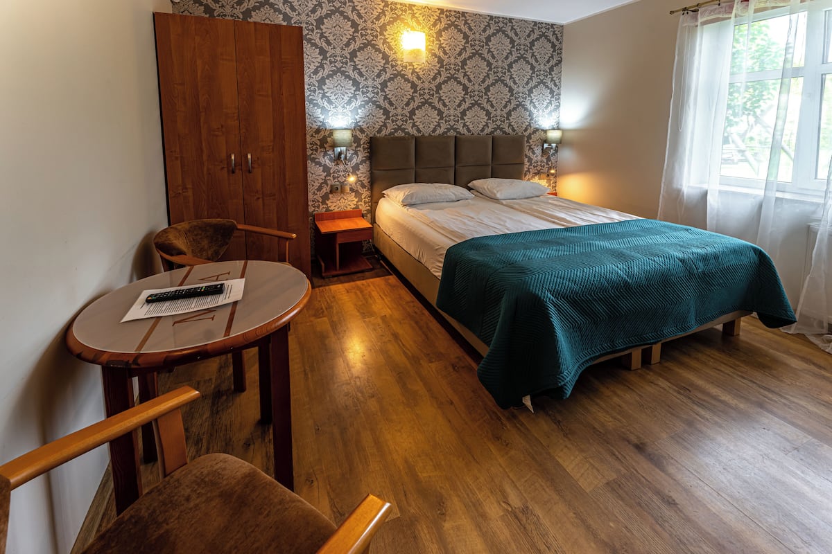 Une chambre à coucher avec un lit, une armoire en bois, une petite table avec une télécommande et une chaise.
