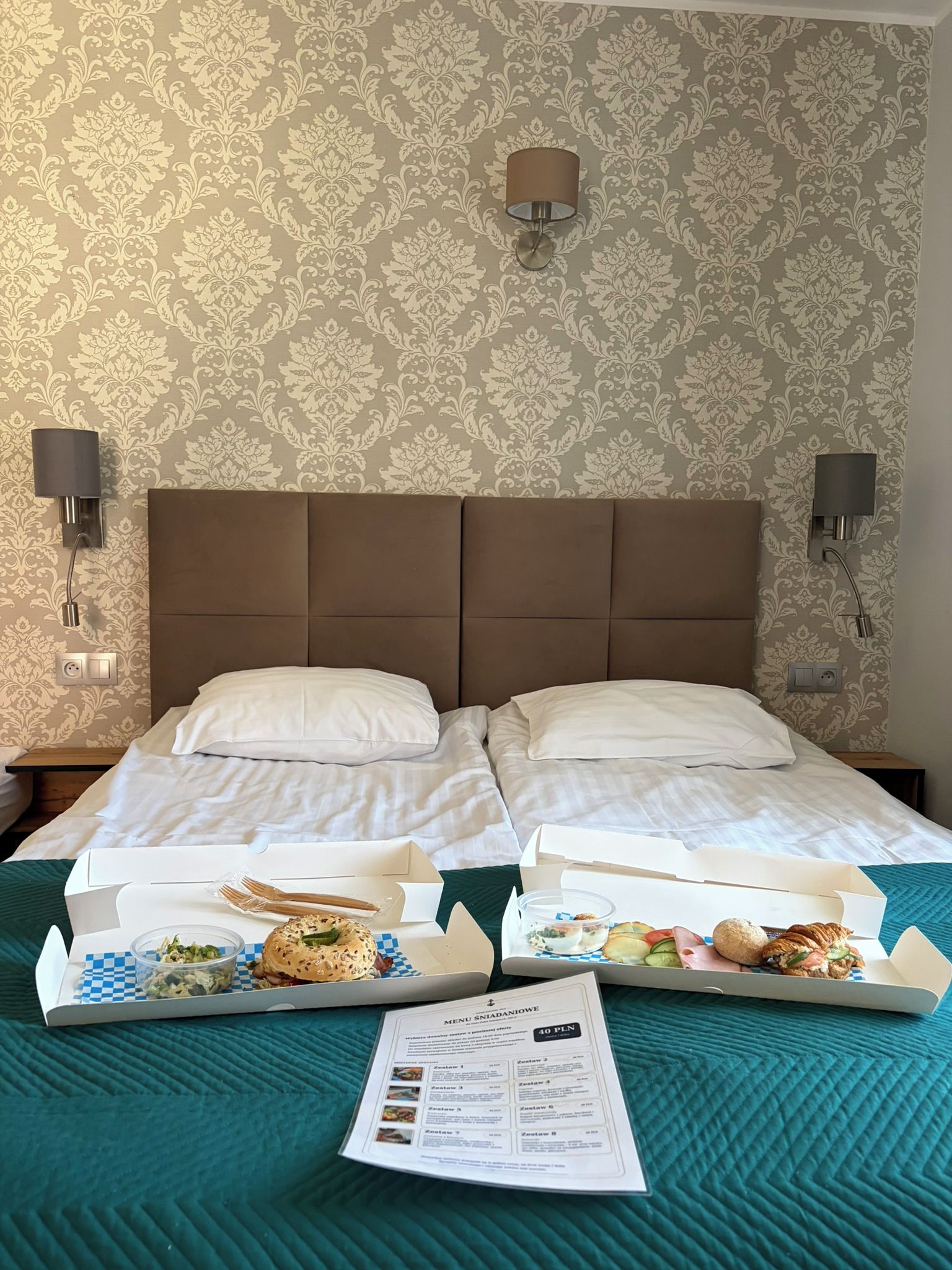 A hotel room with a large bed, two bedside lamps, and a menu on the bed.
