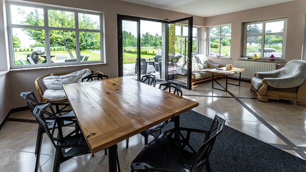 Un vaste espace de vie comprenant une table à manger en bois, des chaises noires, un canapé et un fauteuil.