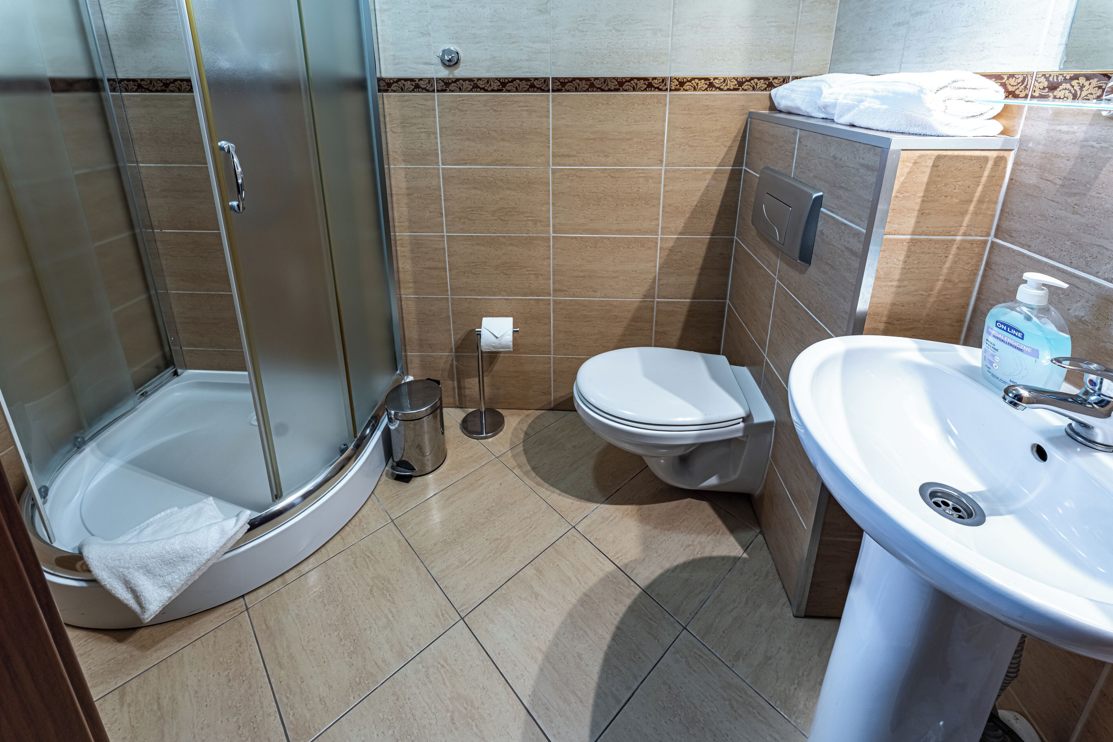 A bathroom with a glass-enclosed shower, a toilet, and a sink.