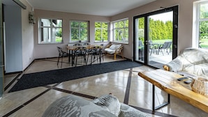Un vaste espace de vie comprenant une table à manger, des chaises, un canapé et une grande fenêtre donnant sur l’extérieur.