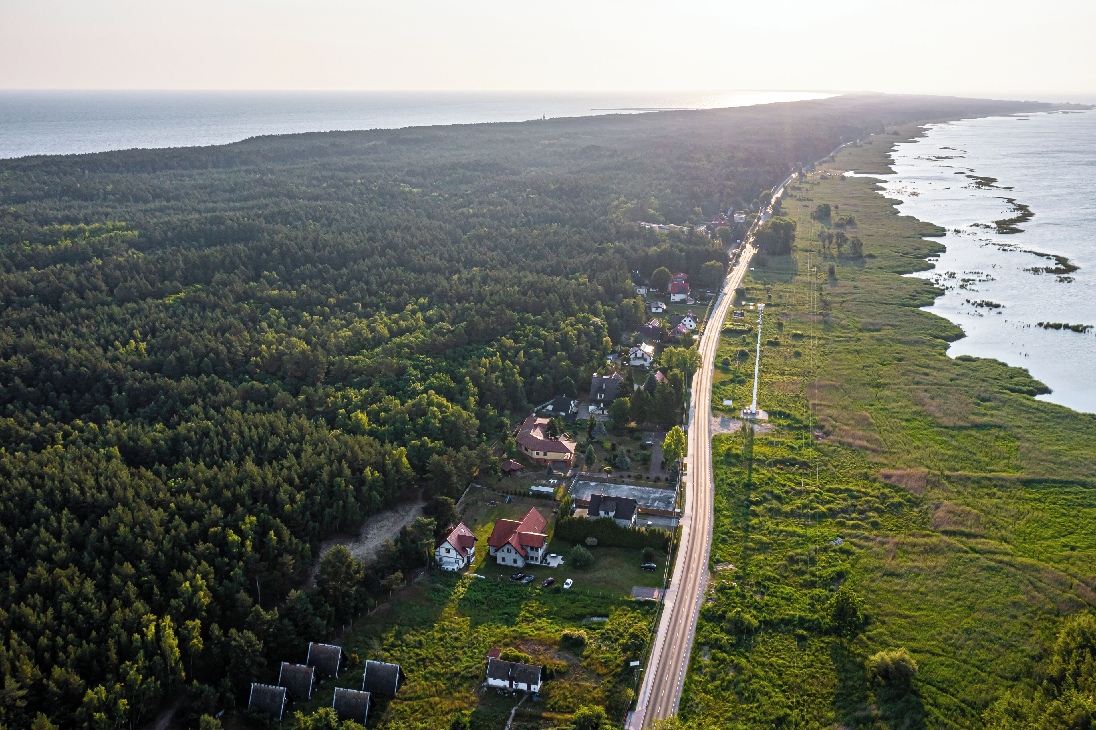 Vista aérea de una zona costera con carretera, casas y bosque denso.
