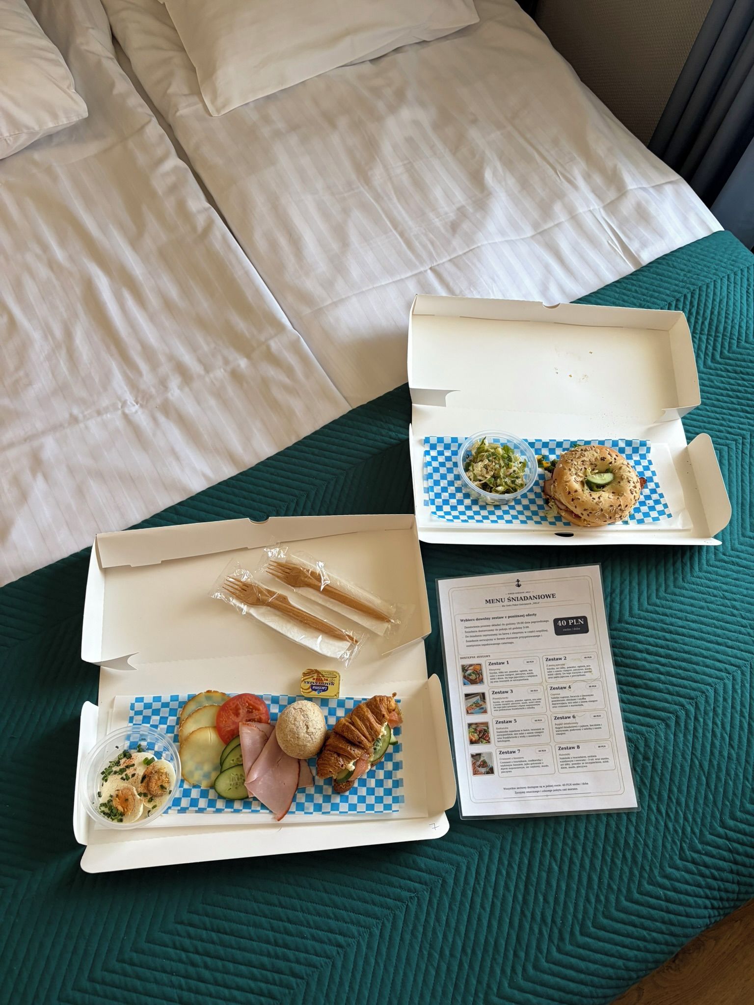 Two open food boxes on a bed with a menu.