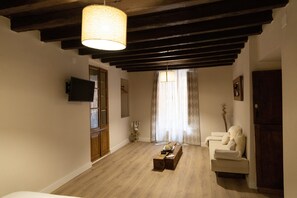Una sala de estar con piso de madera, un sofá, una mesa de centro y un televisor montado en la pared.