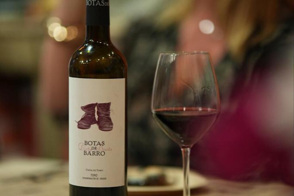 Una botella de vino con etiqueta y una copa de vino tinto.